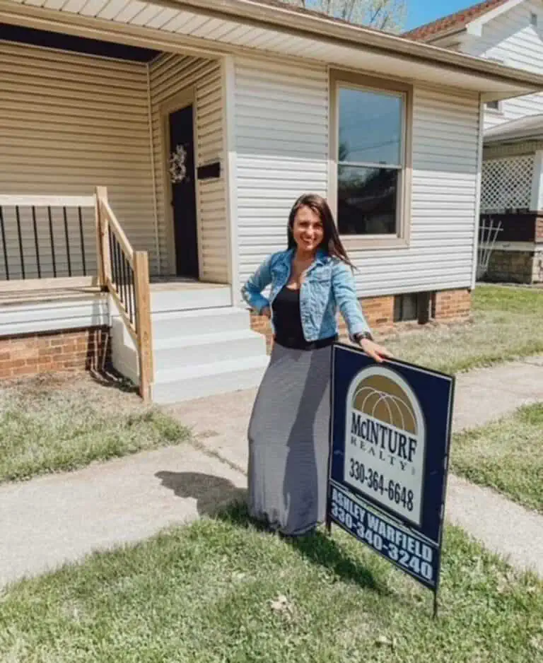 Ashley Herron with a McInturf Realty for sale sign in a yard.