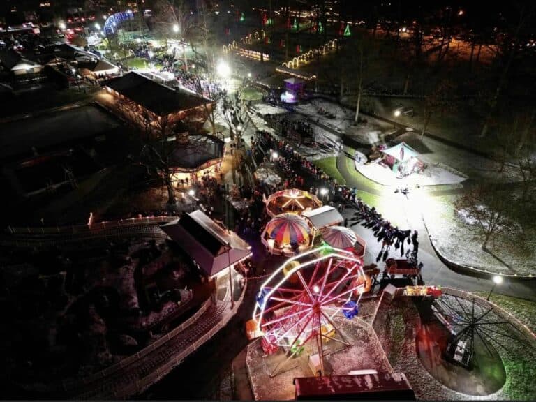 Overhead image of McInturf Realty's Christmas at the Park event featuring Christmas lights, amusement park rides, and a crowd attending the event.