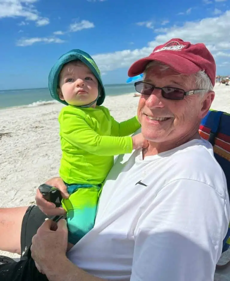 Jan McInturf with his grandchild on the beach.